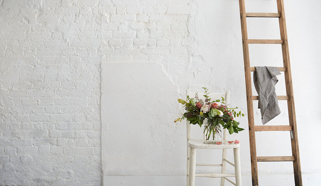 Cut flowers and ladder in whitewashed London studio  UK