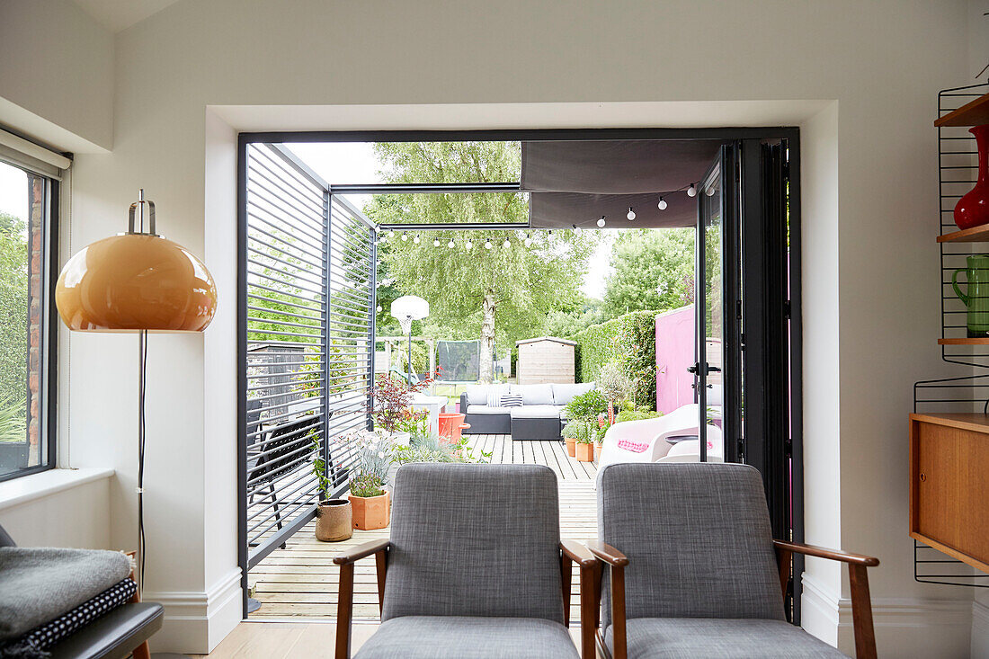 Pair of grey retro style armchairs with view to garden terrace from modernised Preston home  Lancashire  England  UK