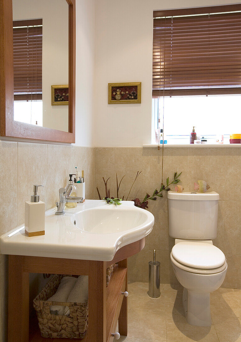 White ceramic basin and toilet with square mirror in bathroom of New Malden home, Surrey, England, UK