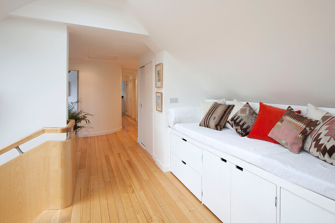 White storage bench with assorted cushions in hallway landing of modern Essex home UK