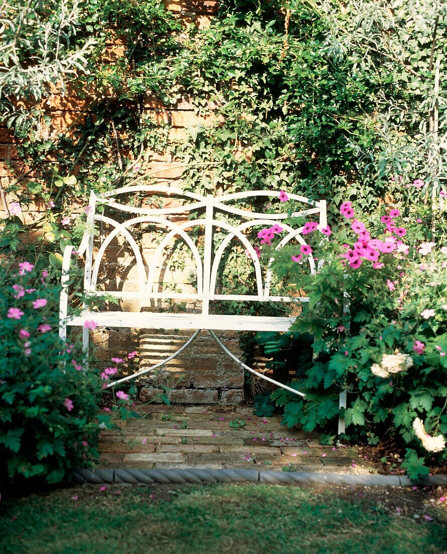 Weiße Gartenbank im heimischen Garten mit Blumen