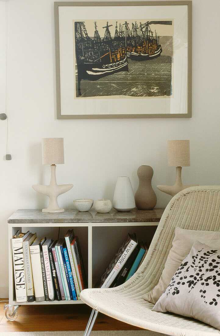 Chair with cushion beside bookcase under artwork