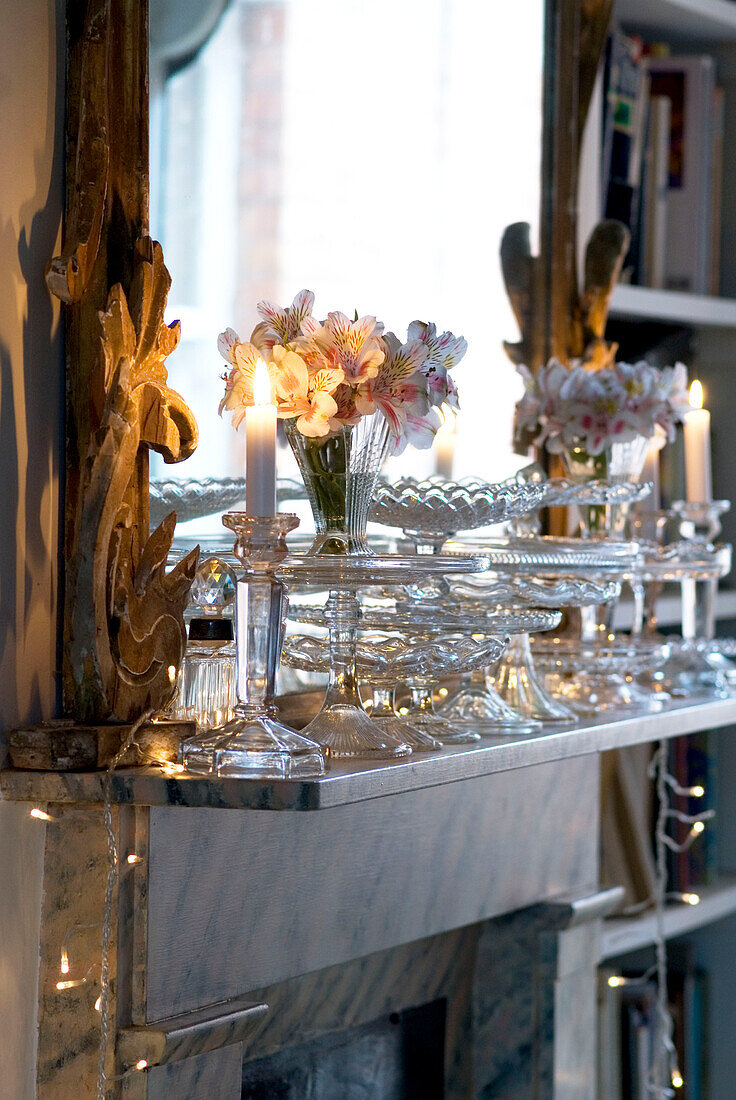 Detail of marble fireplace in living room decorated with vintage glassware and fairy lights