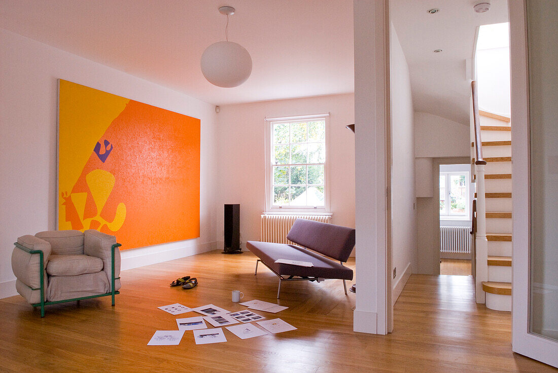 Sofa and armchair in open plan laminate apartment with modern art