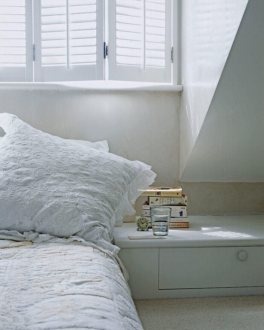 Glass of water and books on bedside table