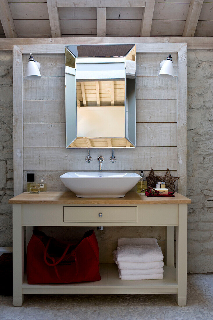 Wash stand on wooden panelled unit set against exposed stone