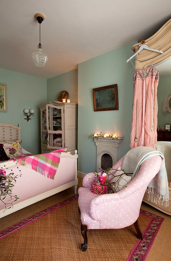 Pink spotted armchair in green pastel bedroom with painted furniture