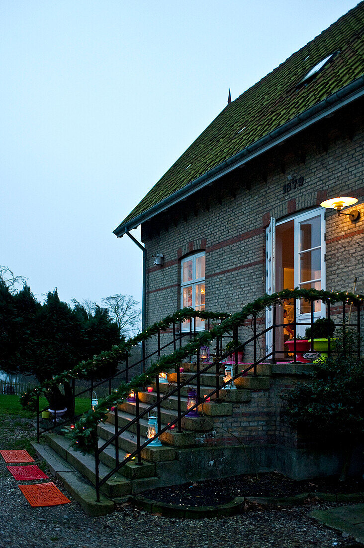 Lit lanterns on steps of Odense home with clear sky