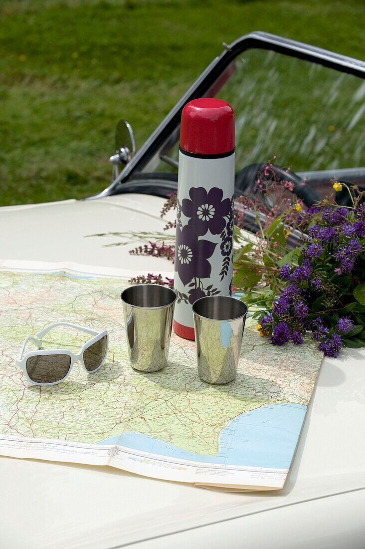 Getränkeflasche und zwei Tassen auf einem Oldtimer