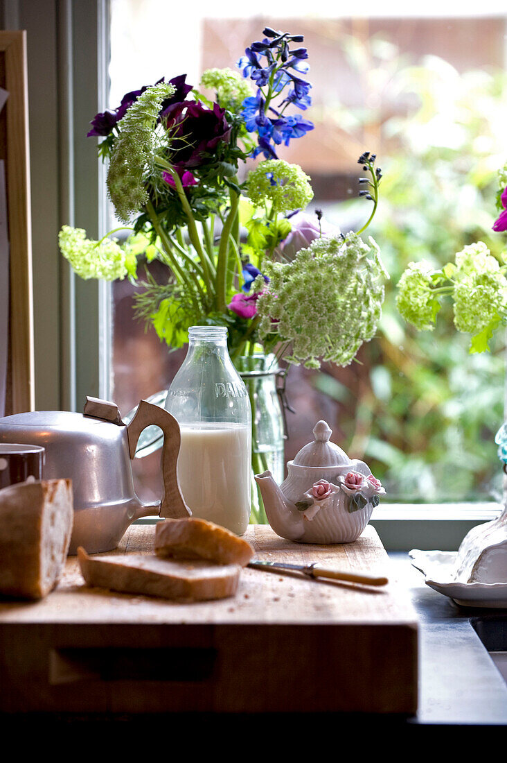 Küchenarbeitsplatte mit Schneidebrett, Küchenutensilien und Blumenständer