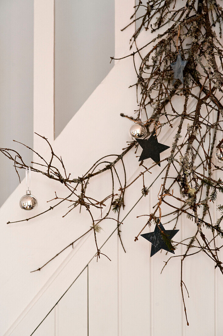 Silver baubles and star shaped decorations on pine branch in London home