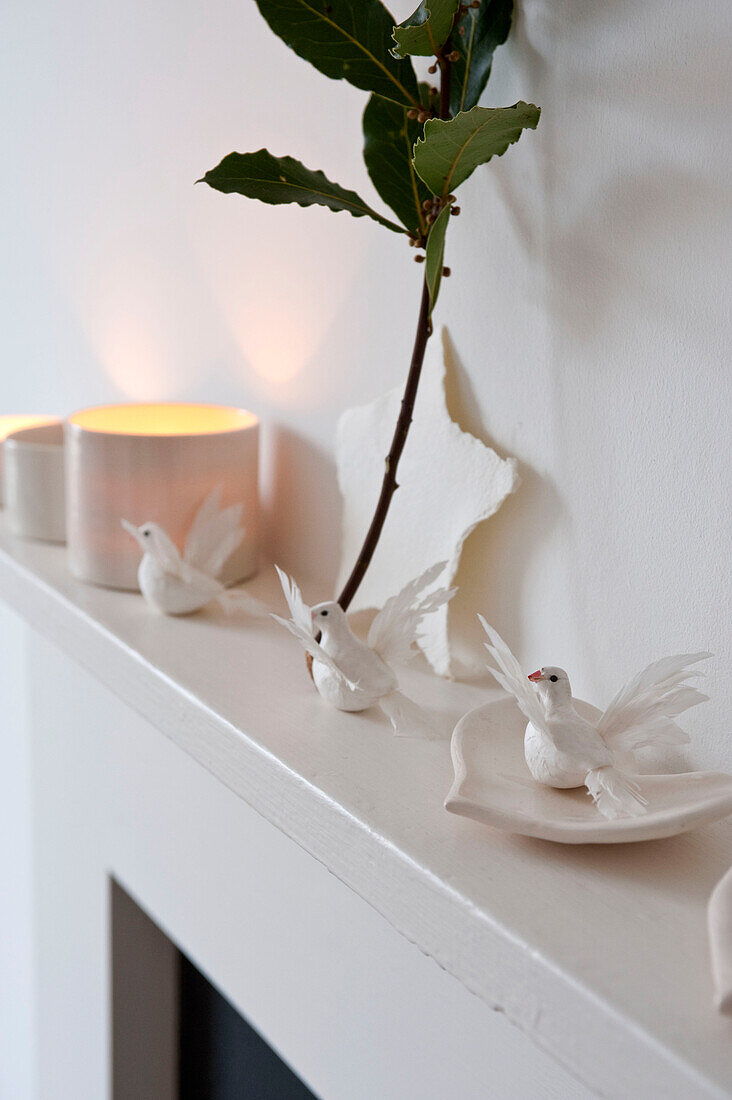 Sprig of leaves on mantlepiece with white bird ornaments in Richmond home