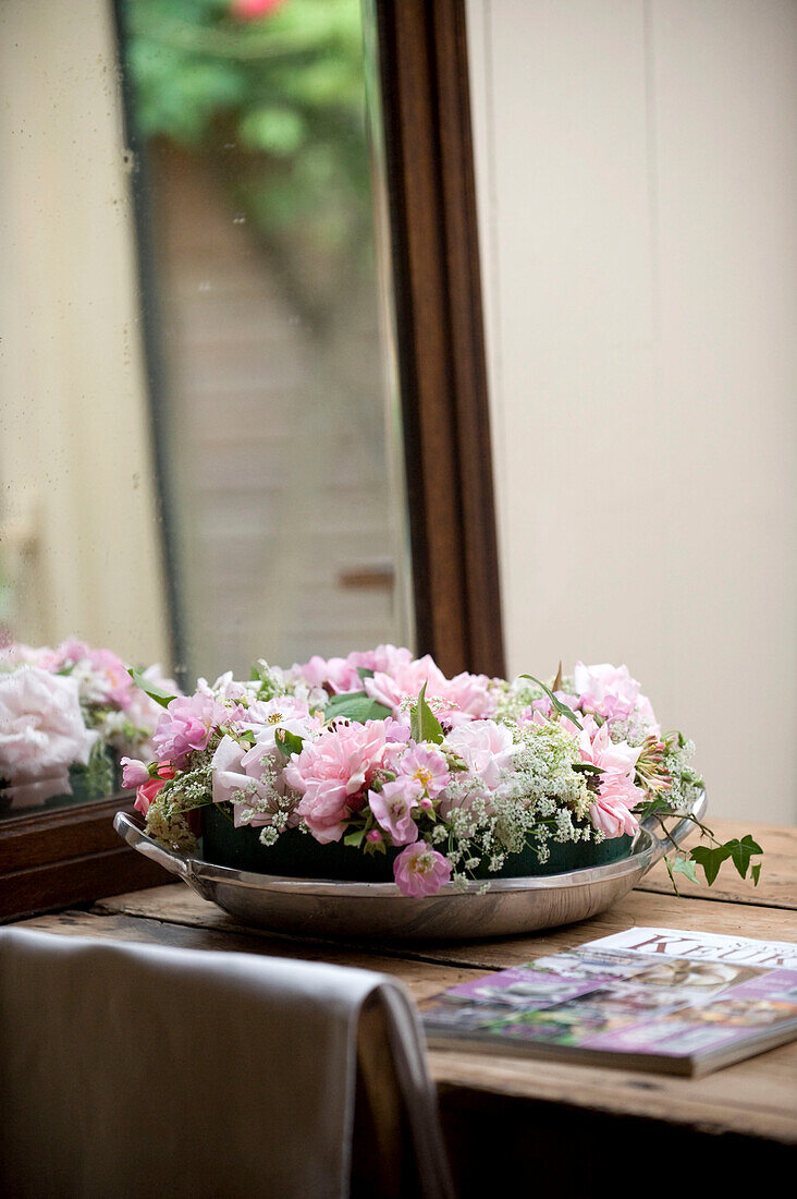 Pink flowers in metal tray reflected in mirror