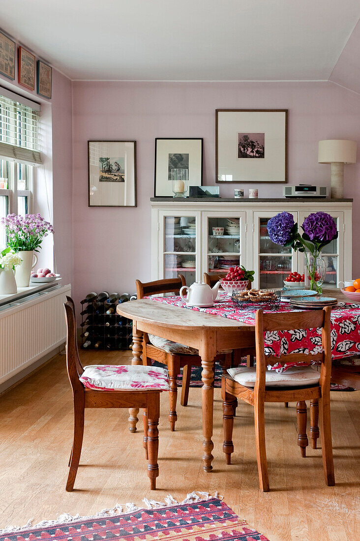 Wooden dining table and chairs with glass fronted cabinet in London home UK