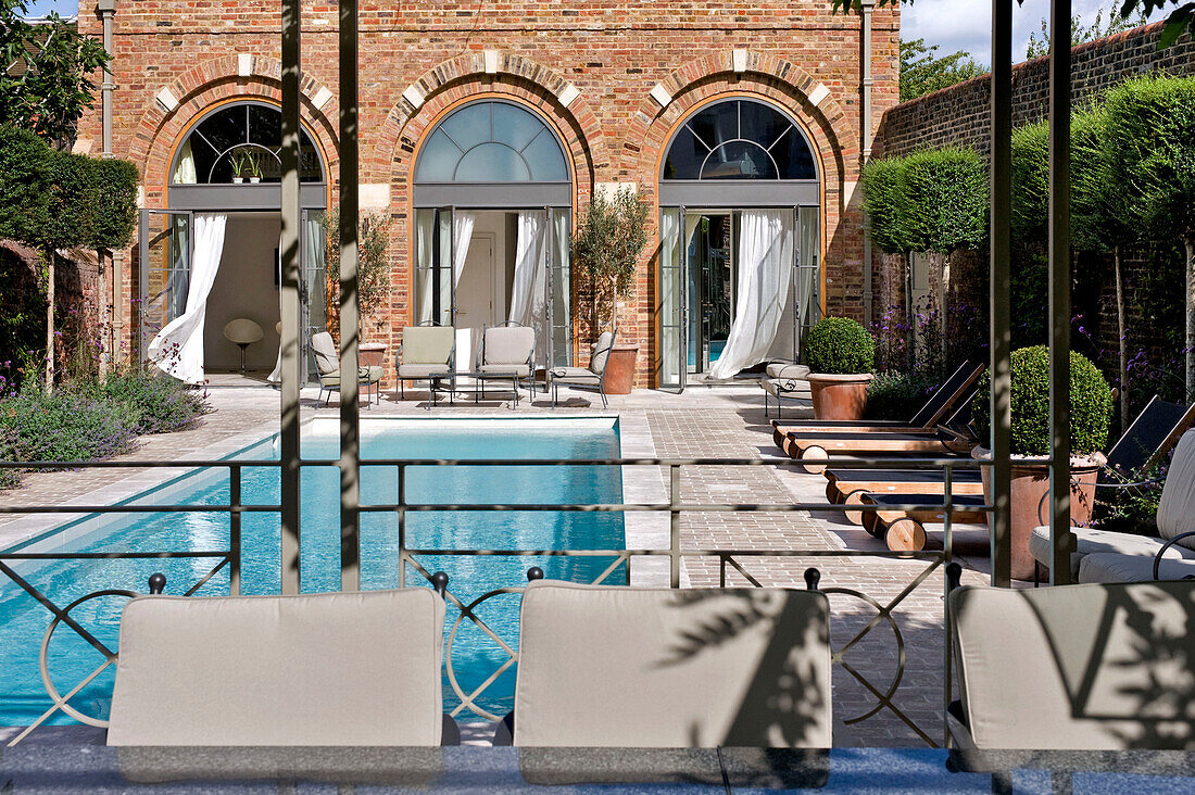 Sunlit swimming pool and brick exterior of West London townhouse England UK