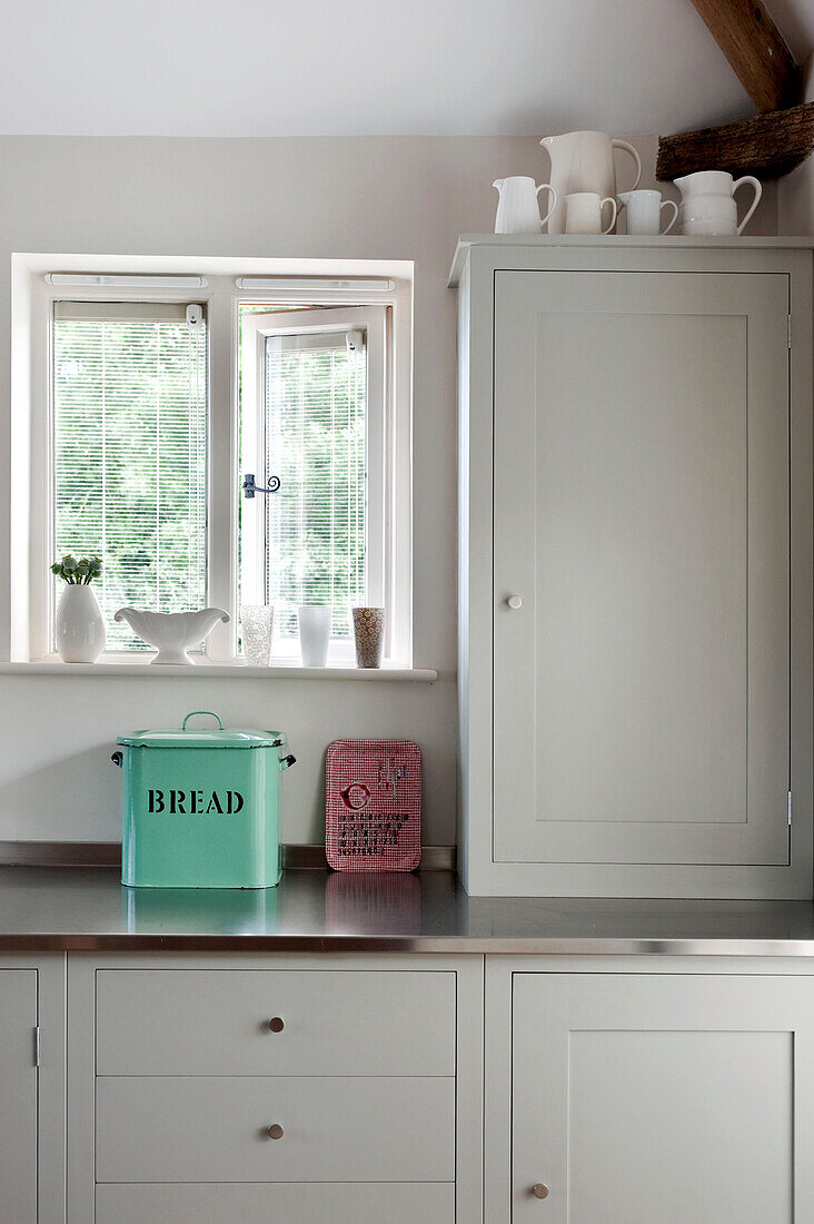 Breadbin below window with homeware in kitchen of Suffolk home England UK