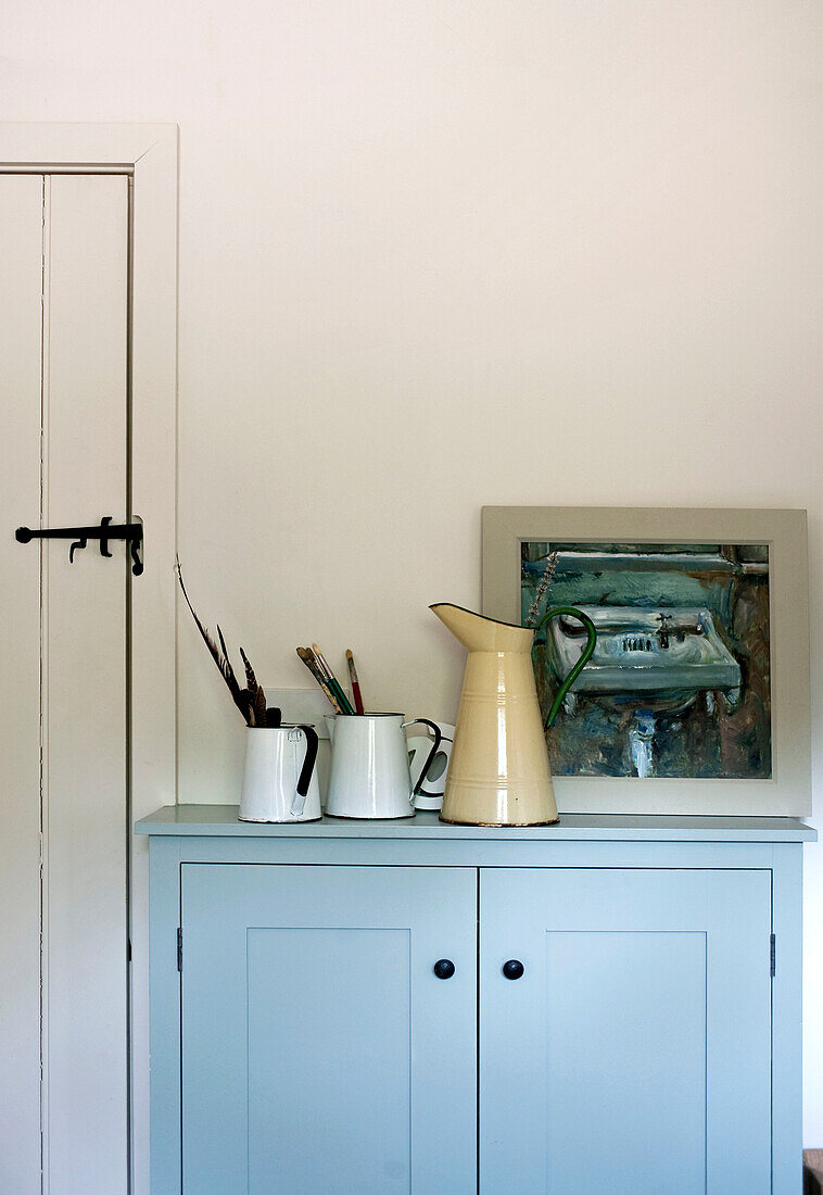 Paintbrushes in metal jugs with artwork in Suffolk family home England UK