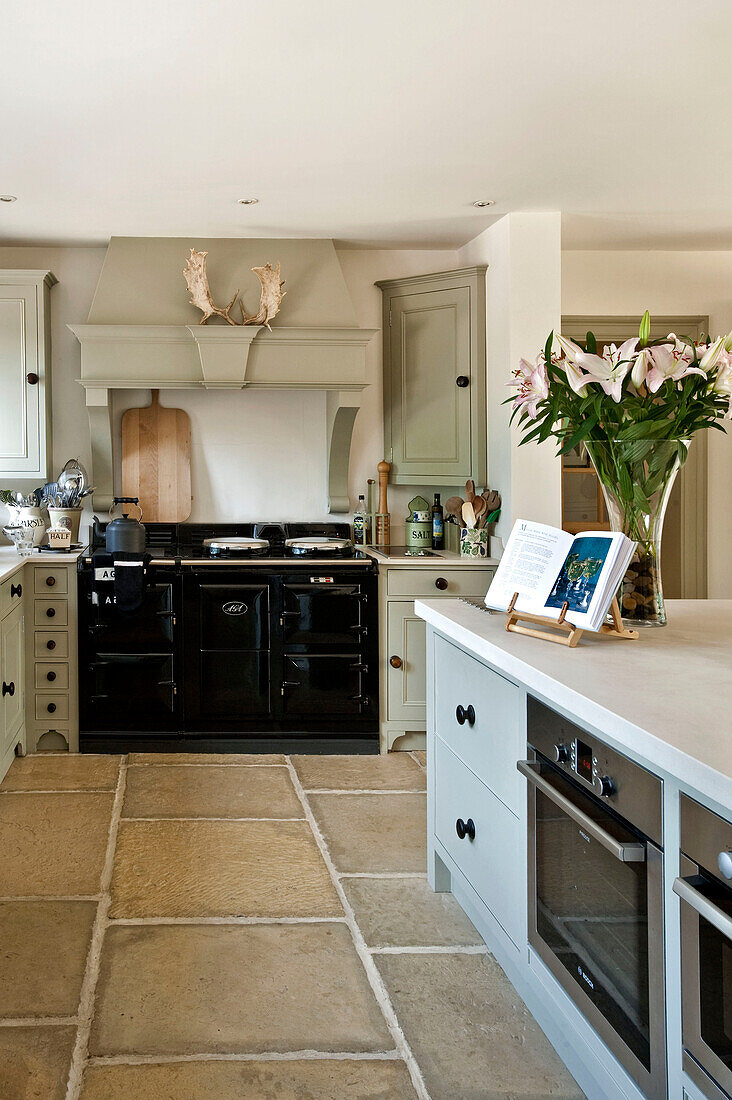 Schwarzer Herd in einer Küche aus Steinplatten mit pastellgrünen Einbaumöbeln in der Küche eines Hauses in Canterbury, England, Vereinigtes Königreich