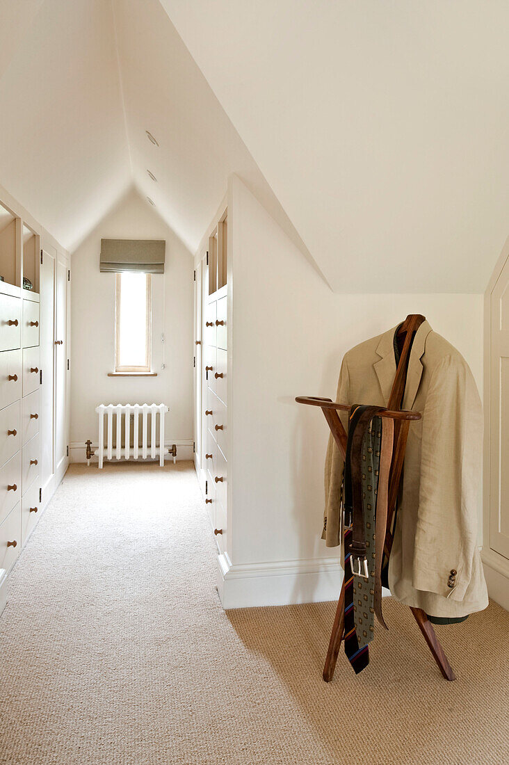 Cream blazer hangs with ties on antique trouser press in dressing room of Canterbury home England UK