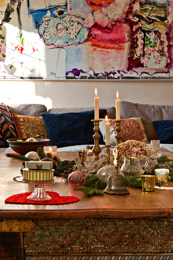 Christmas ornaments and lit candles on low carved coffee table in Forest Row home, Sussex, England, UK