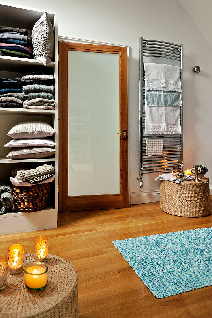 Lit candles and storage unit in bathroom with frosted glass door in Forest Row family home, Sussex, England, UK