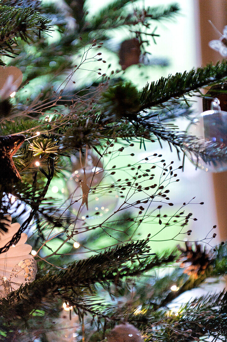 Fairylights and glass baubles in Christmas tree, Forest Row family home, Sussex, England, UK