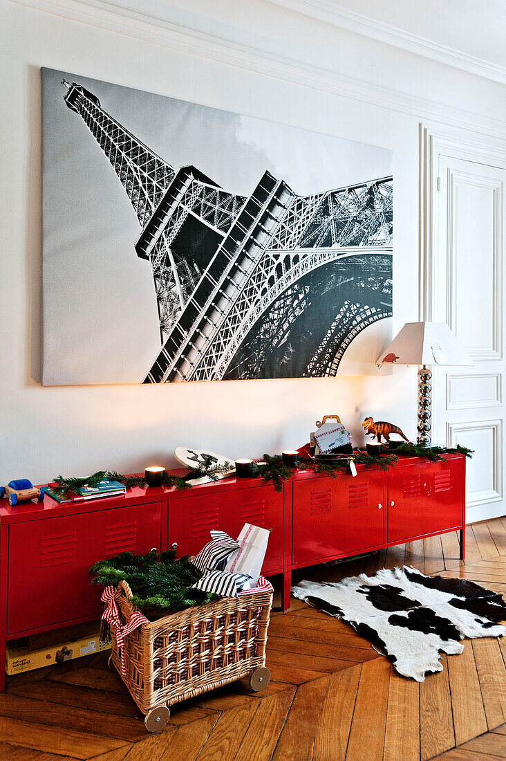Large print of Eiffel Tower above red sideboard with Christmas decorations in Paris apartment, France