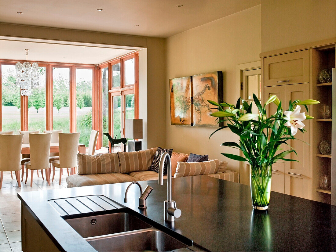 Vase of cut lilies in open plan kitchen dining and sitting area in rural Suffolk home England UK