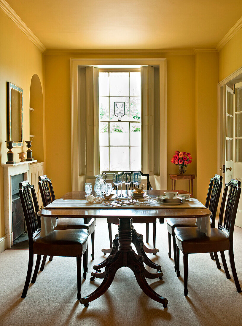 Glassware on table in yellow dining room of rural Suffolk home England UK