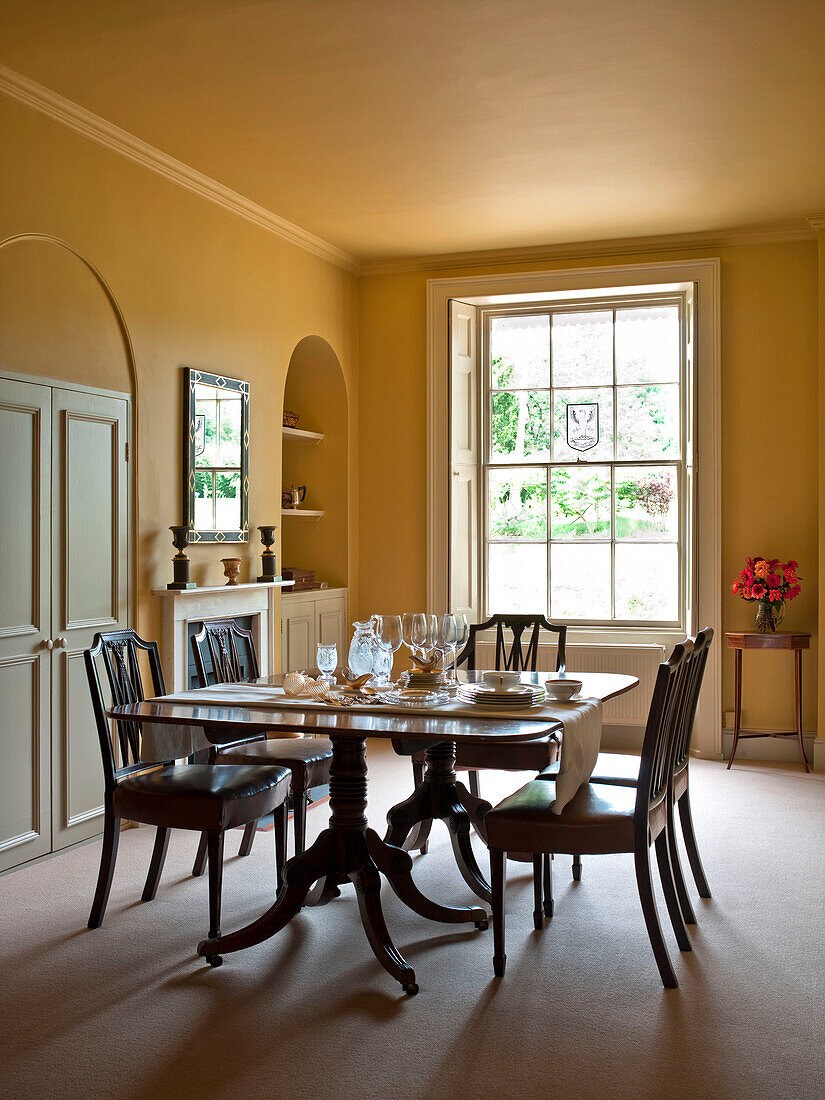 Gläser auf dem Tisch im gelben Esszimmer eines Landhauses in Suffolk, England UK