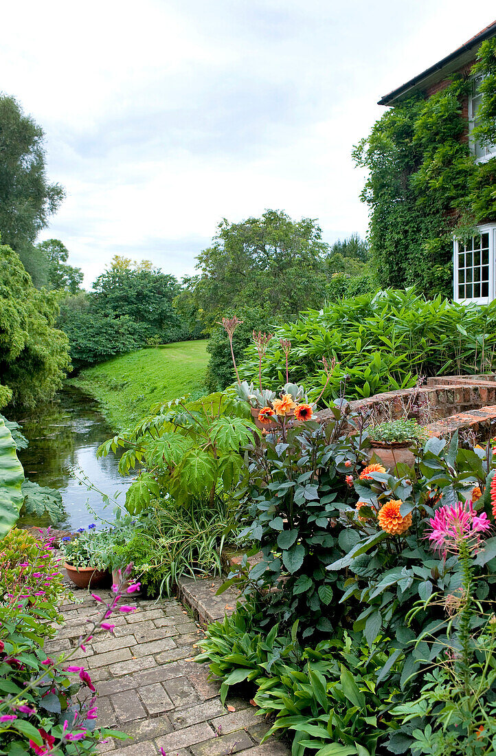 Brick path and footbridge in garden exterior of rural Suffolk home England UK