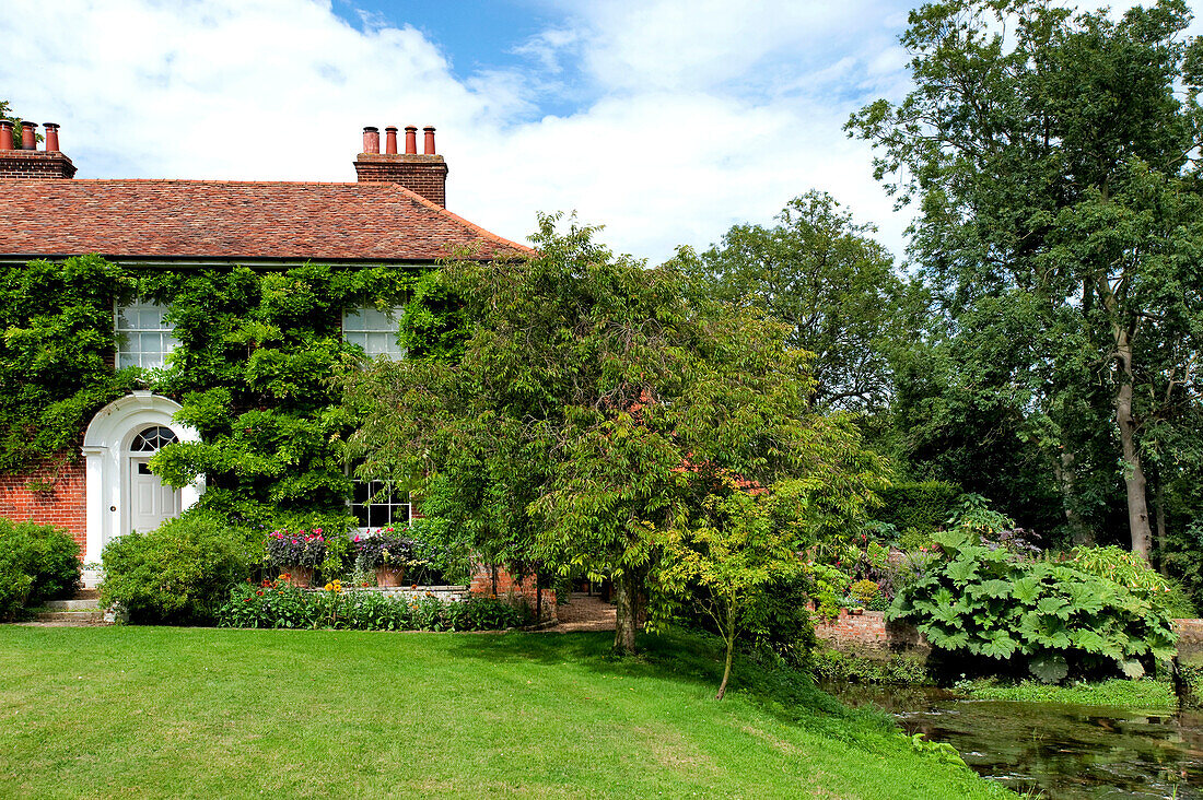 Lawned garden exterior of rural brick Suffolk country house England UK