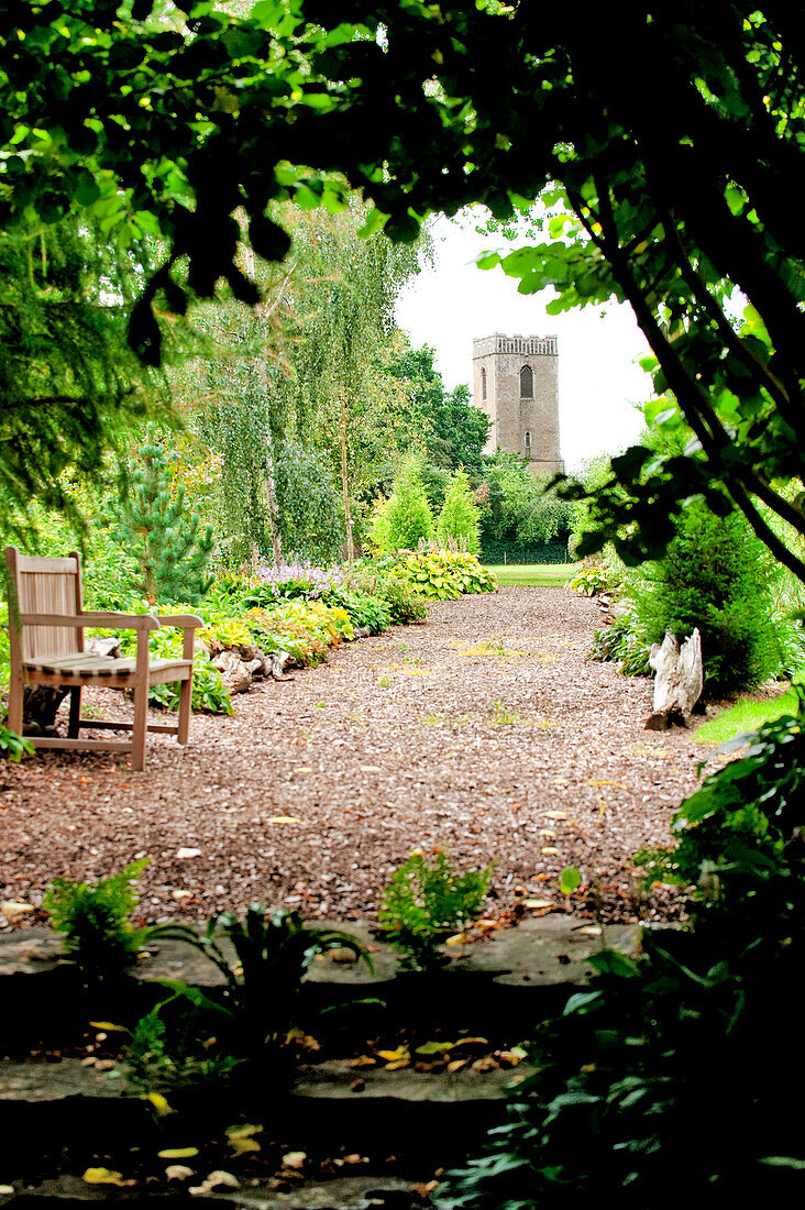 Bench seat on gravel path under shade of tree in Suffolk England UK