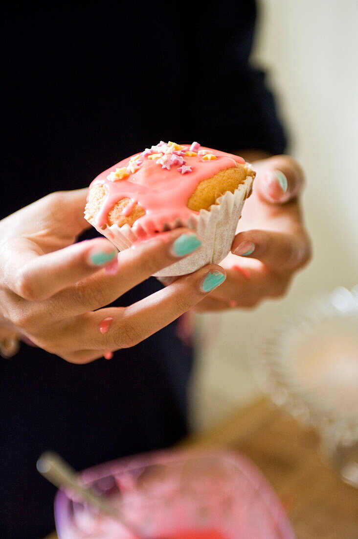 Frau glasiert Muffins in einem Haus in Buckinghamshire, England, Vereinigtes Königreich