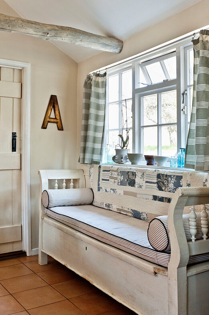 Cushioned window seat in Suffolk farmhouse kitchen, England, UK