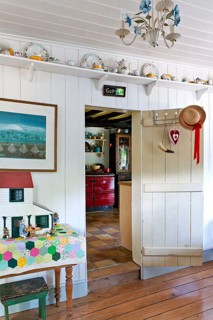 Dolls house in hallway with shelf above door and view into kitchen of Essex home, England, UK