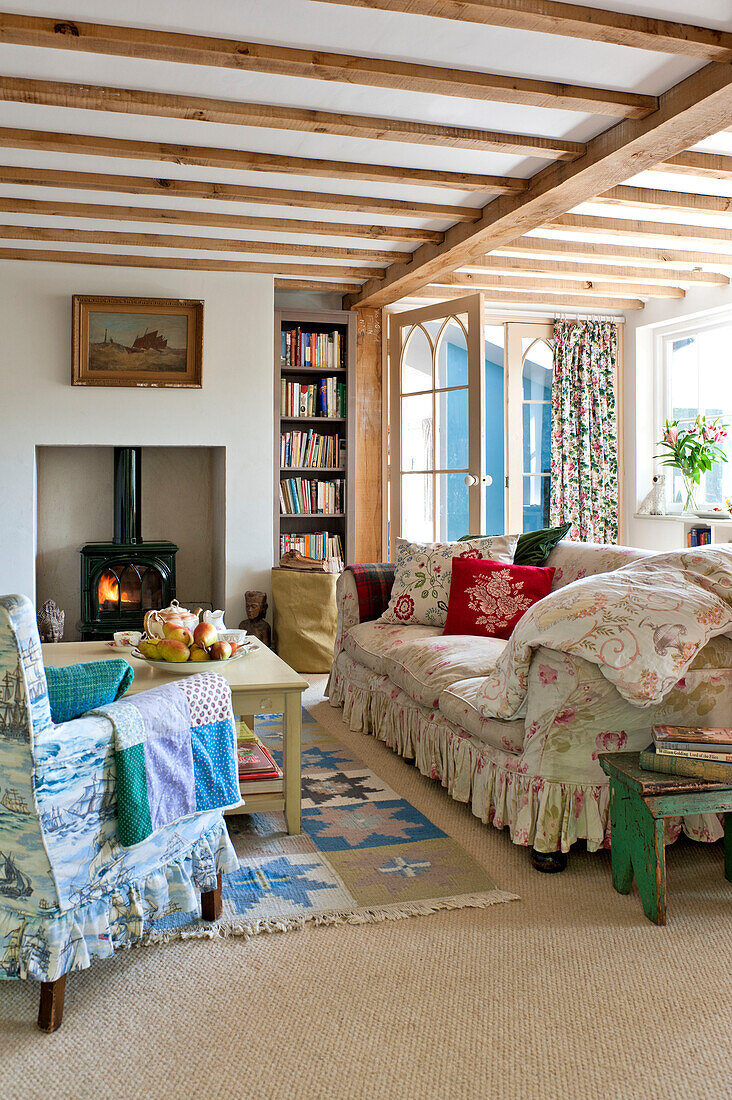 Beamed living room with wood burning stove in Essex home, England, UK