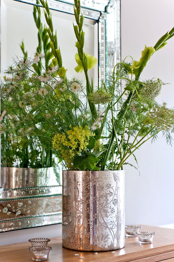 Flower arrangement in silver vase on sideboard in Middlesex family home, London, England, UK