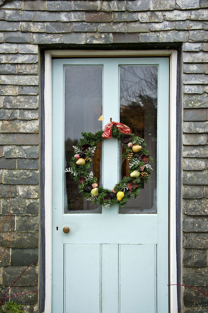 Christmas garland on front door of stone farmhouse, Cornwall, England, UK