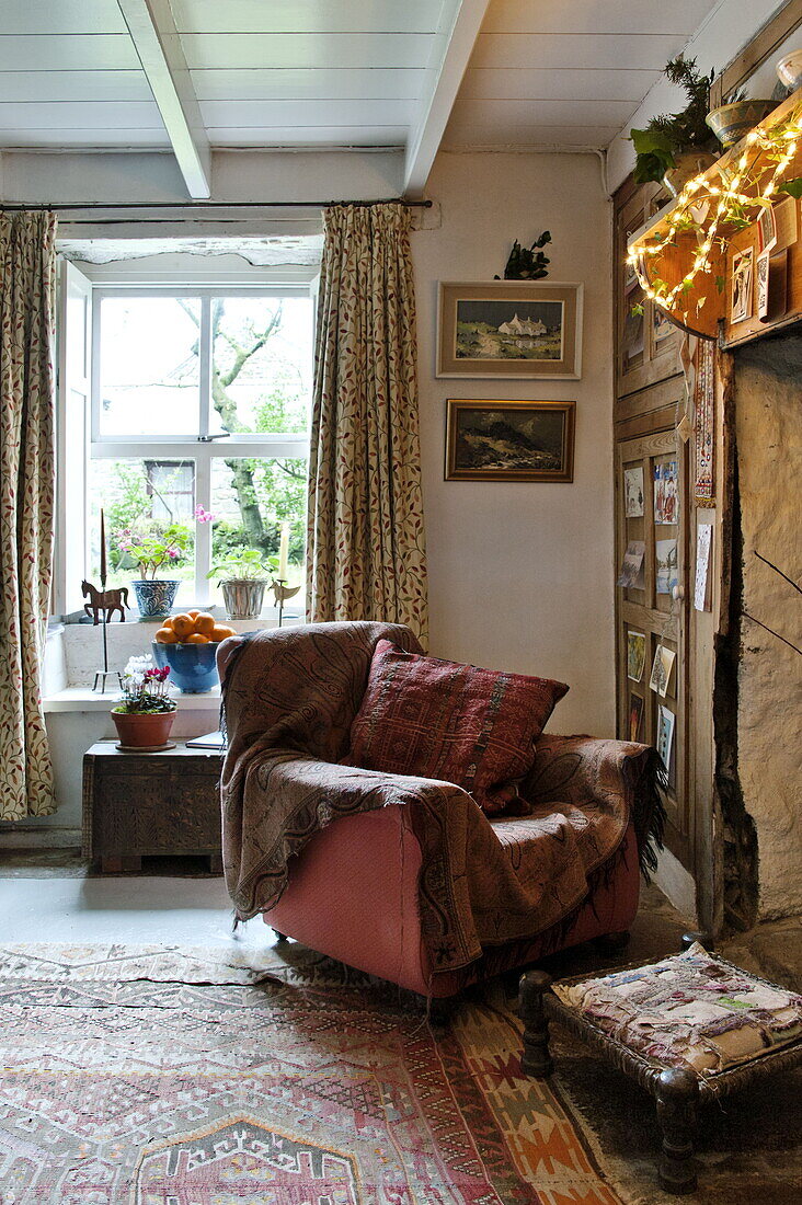 Armchair at living room fireplace in farmhouse, Cornwall, England, UK