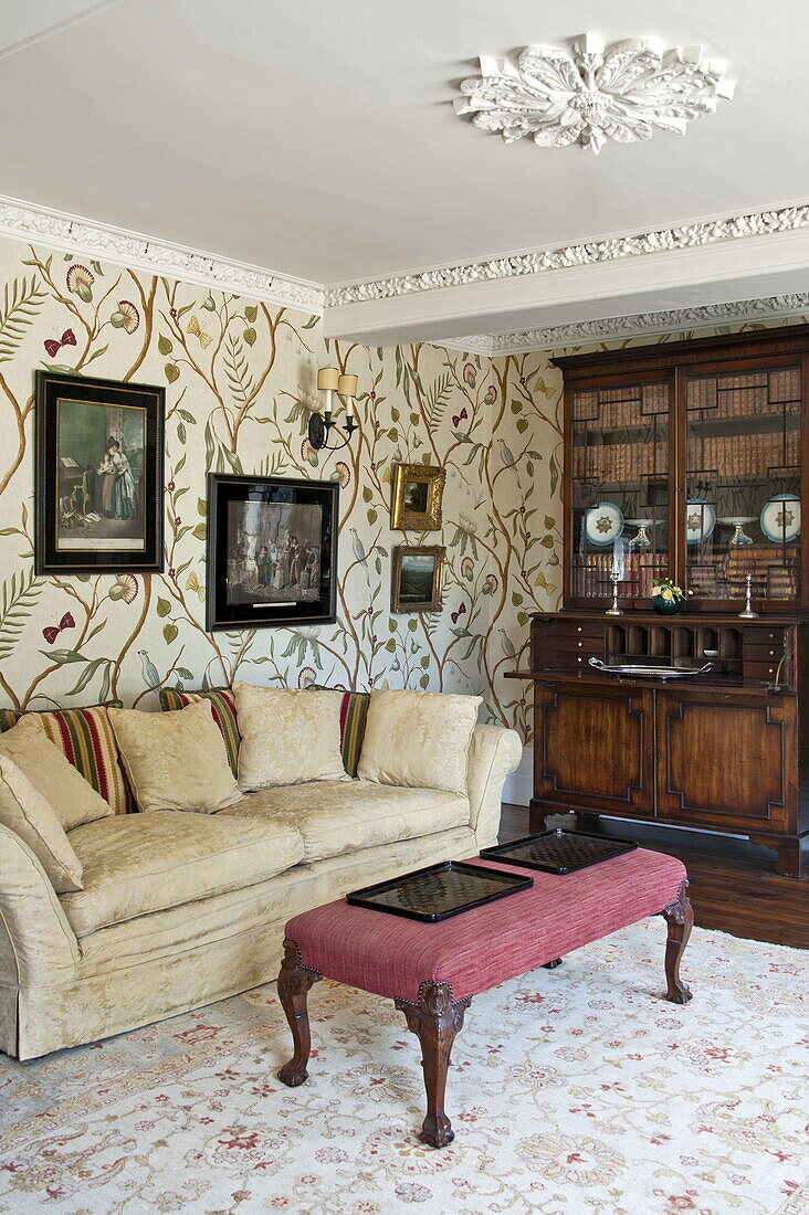 Artwork above sofa in living room with patterned wallpaper, contemporary Suffolk country house, England, UK