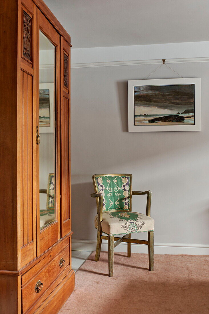 Antiker Holzschrank und Kunstwerk mit Stuhl im Schlafzimmer von Padstow cottage, Cornwall, England, UK
