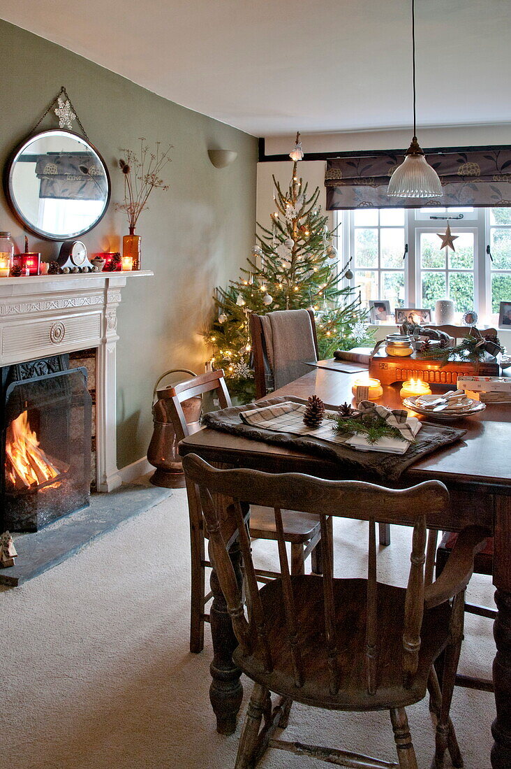 Oval mirror above lit fire in dining room of Shropshire cottage, England, UK