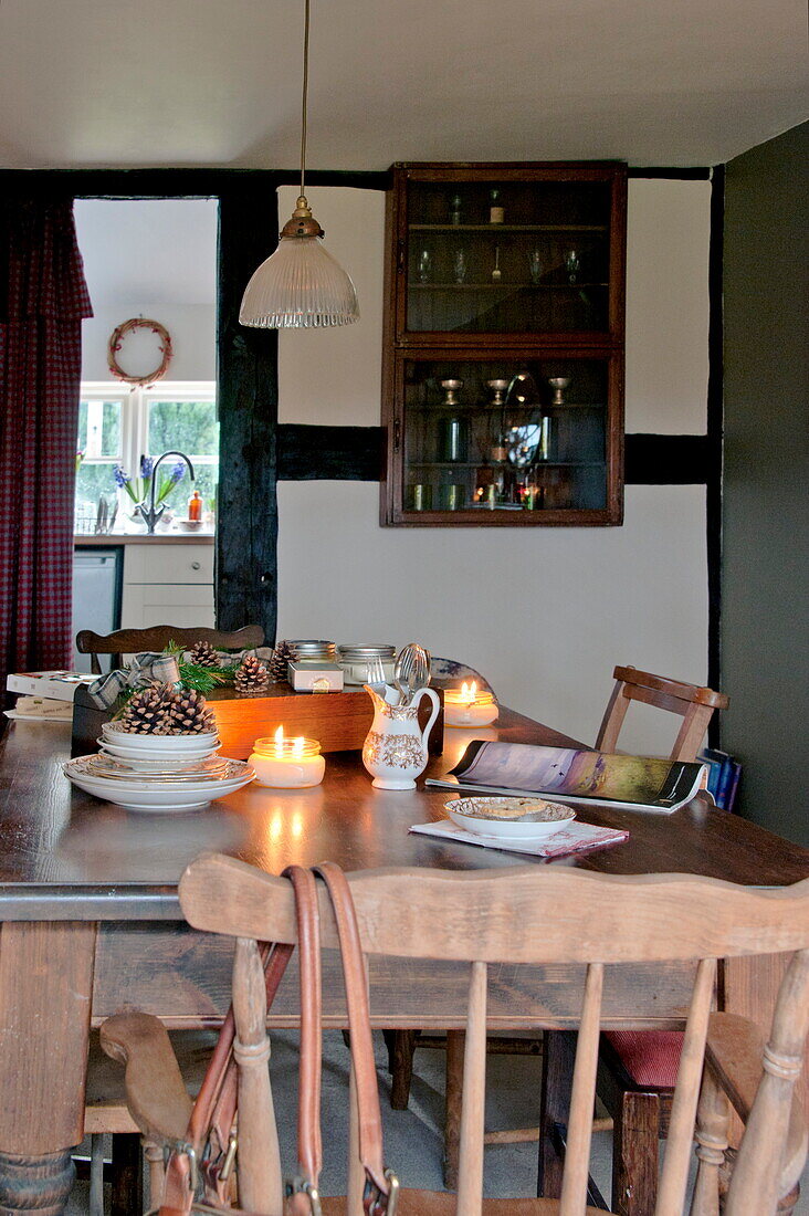 Lit candles and wall mounted cabinet in dining room of Shropshire cottage, England, UK