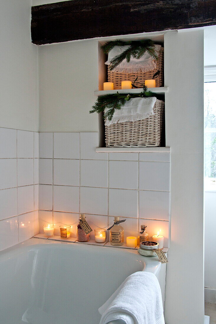 Lit candles in tiled white bathroom of Shropshire cottage, England, UK