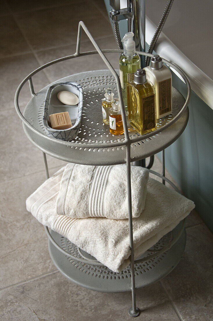 Toiletries and folded towels on bath stand in contemporary Suffolk country house, England, UK