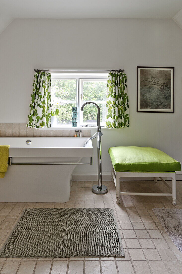 Leaf patterned curtains at window in bathroom with lime green seat cover in contemporary Suffolk/Essex home, England, UK