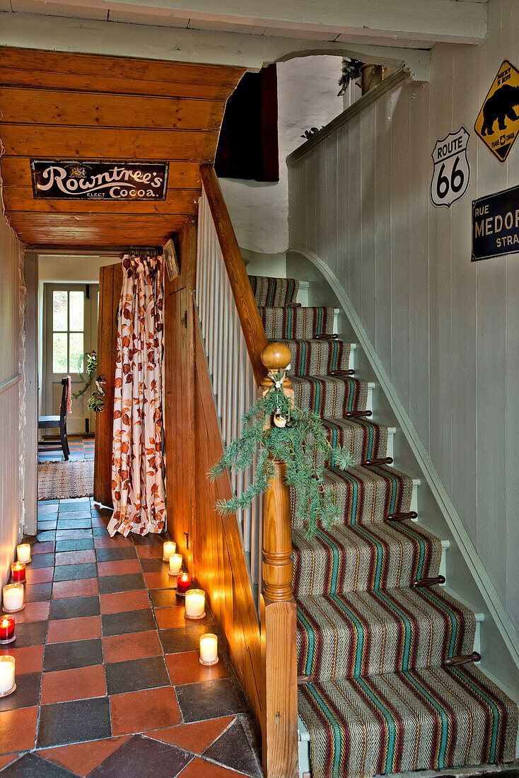 Brennende Kerzen im gefliesten Flur mit Teppichtreppe in einem Haus in Tregaron, Wales, UK