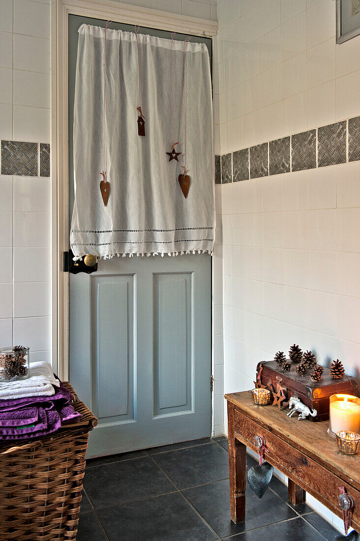 Linen bathroom door curtain with lit candle on wooden side table in Tregaron home Wales UK