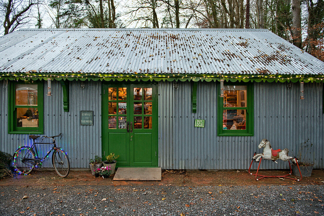 Fahrrad mit Oberlichtern an der Außenseite eines grün gestrichenen Wellblechladens in Tregaron, Wales, Vereinigtes Königreich